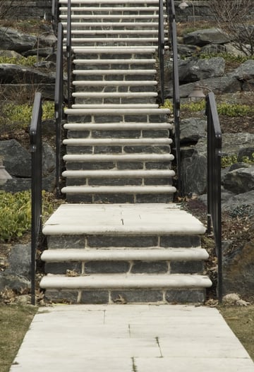Stone and concrete stairway with black iron railings up rocky hillside